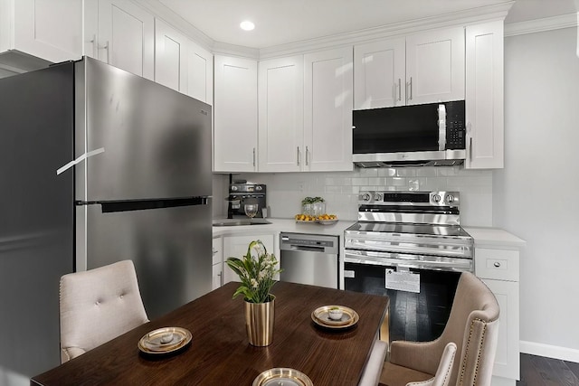 kitchen featuring tasteful backsplash, white cabinetry, stainless steel appliances, and light countertops