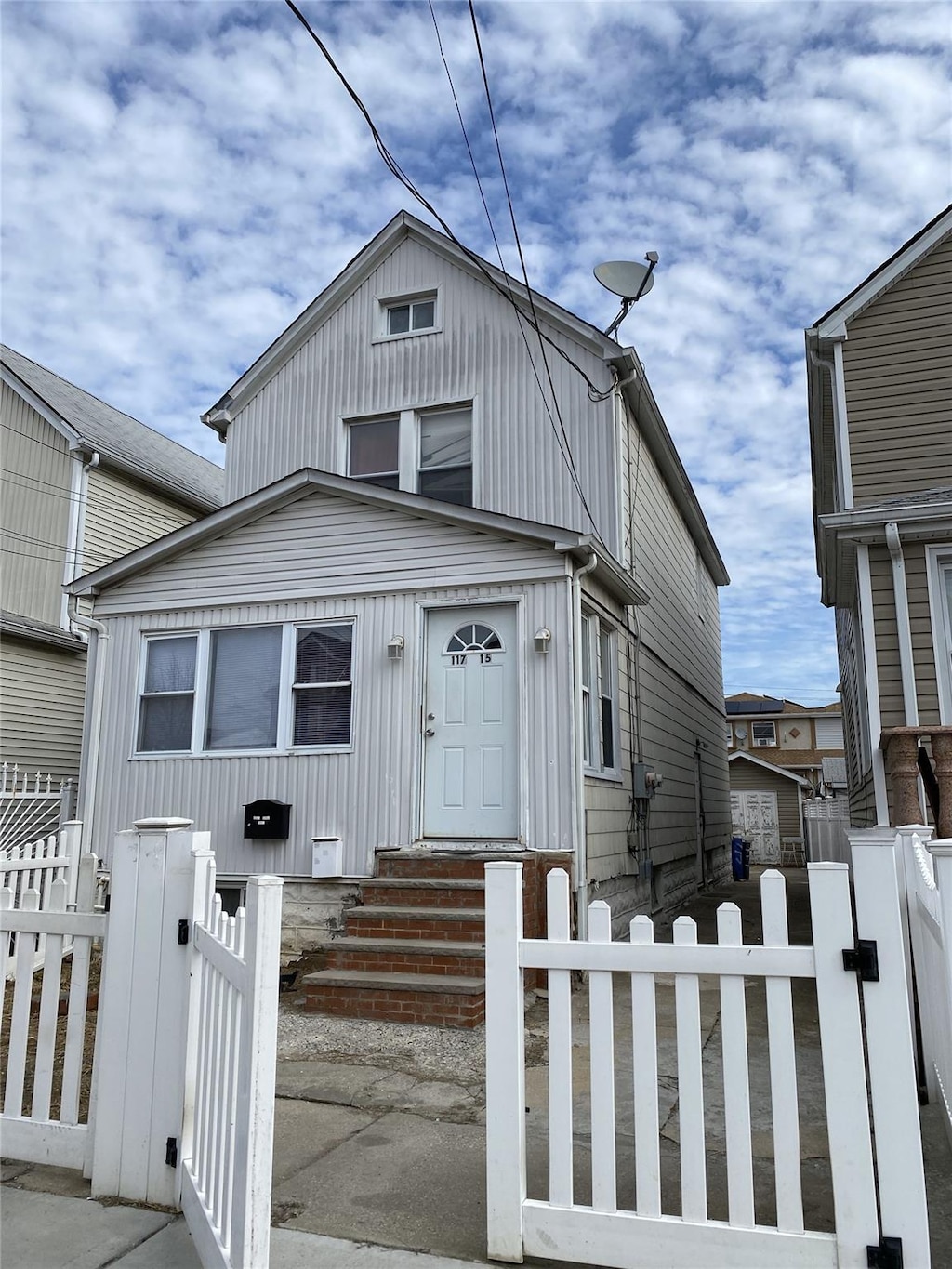 view of front of house with entry steps, a fenced front yard, and a gate