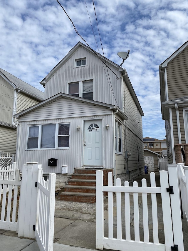 view of front of house with entry steps, a fenced front yard, and a gate