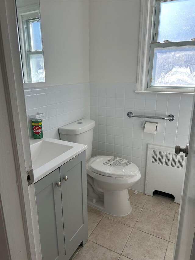 half bathroom with radiator, plenty of natural light, vanity, and toilet