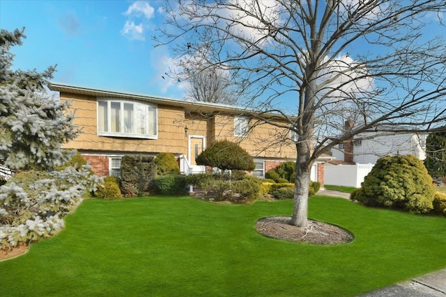 split foyer home featuring fence, a front lawn, and brick siding