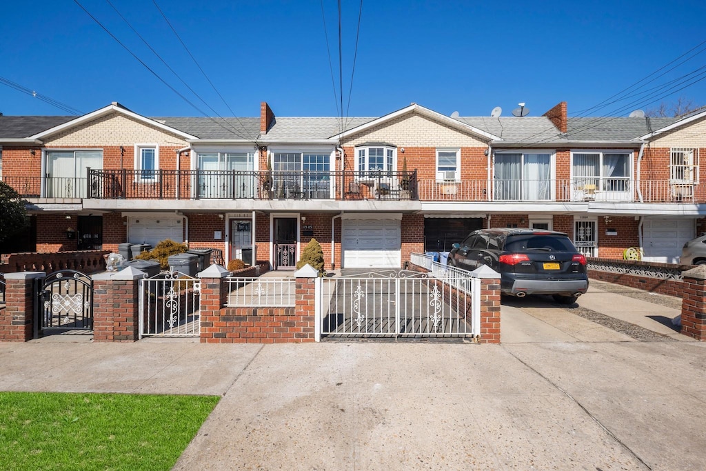 11505 Linden Blvd, South Ozone Park, NY 11420 - townhome / multi-family property with driveway, an attached garage, a gate, and brick siding