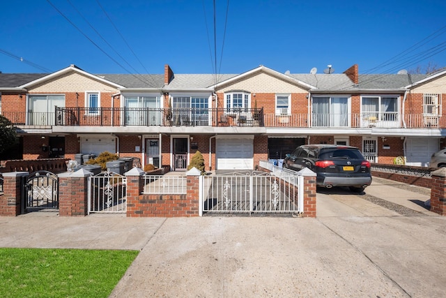 townhome / multi-family property with driveway, an attached garage, a gate, and brick siding