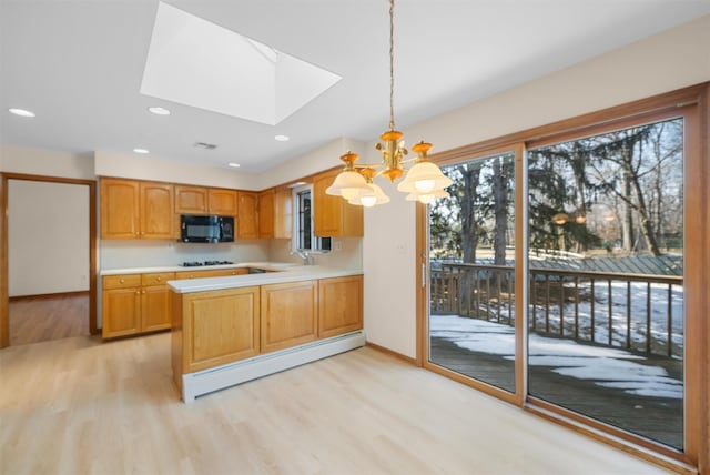 kitchen with pendant lighting, light countertops, baseboard heating, black microwave, and a peninsula