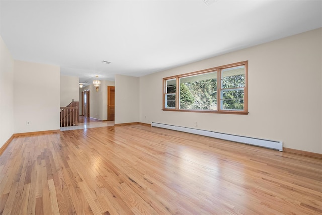 unfurnished room featuring baseboard heating, light wood-type flooring, and baseboards