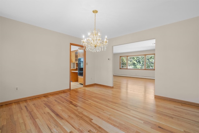 spare room with a baseboard heating unit, baseboards, light wood finished floors, and an inviting chandelier