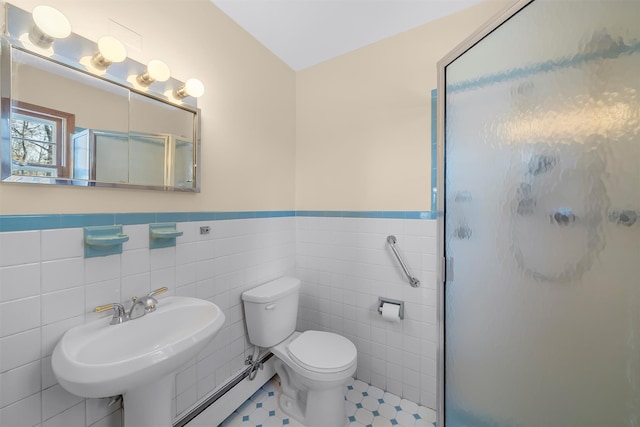 full bath featuring toilet, a wainscoted wall, baseboard heating, a shower stall, and tile walls