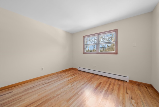 spare room featuring light wood finished floors, a baseboard radiator, and baseboards