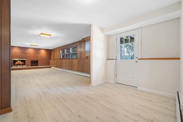 entryway featuring light wood-style floors, a baseboard radiator, a fireplace, and wooden walls