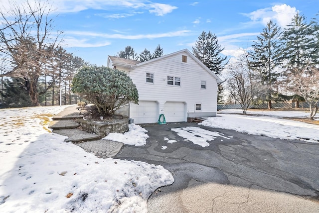 view of snow covered exterior with an attached garage and aphalt driveway