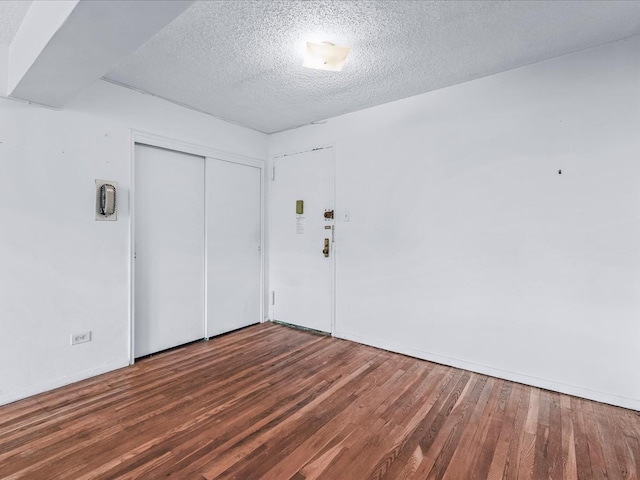 empty room with a textured ceiling and wood finished floors