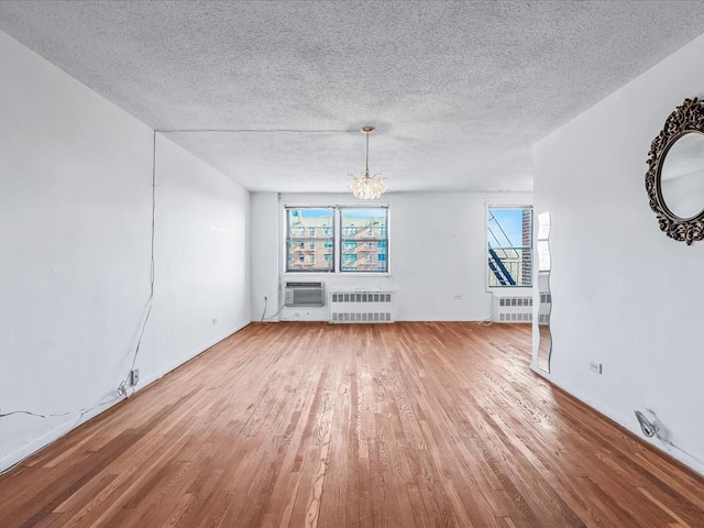 unfurnished living room featuring radiator, plenty of natural light, and wood finished floors