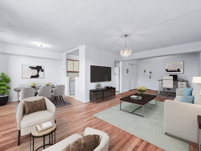 living room with a chandelier, light wood finished floors, and a textured ceiling