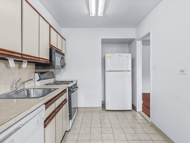 kitchen with white appliances, light countertops, white cabinetry, a sink, and light tile patterned flooring