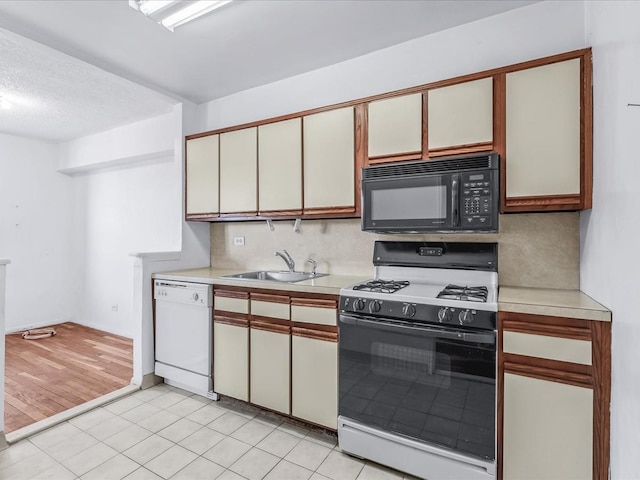 kitchen with tasteful backsplash, light countertops, white cabinetry, a sink, and white appliances