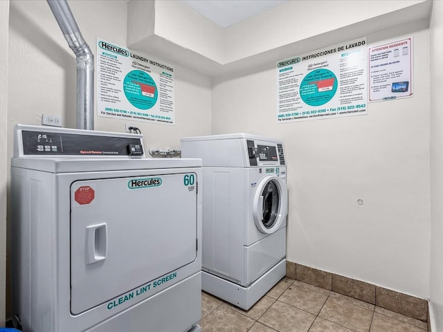 community laundry room with baseboards, washing machine and clothes dryer, and light tile patterned flooring