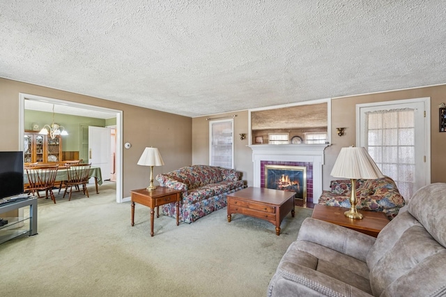 living area with carpet floors, a chandelier, a textured ceiling, and a tiled fireplace