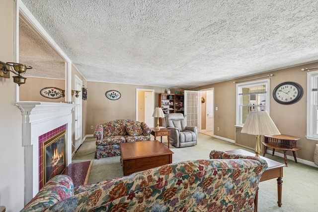 living room with a glass covered fireplace, carpet flooring, a textured ceiling, and baseboards