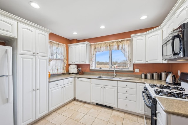 kitchen with white appliances, recessed lighting, a sink, and white cabinets