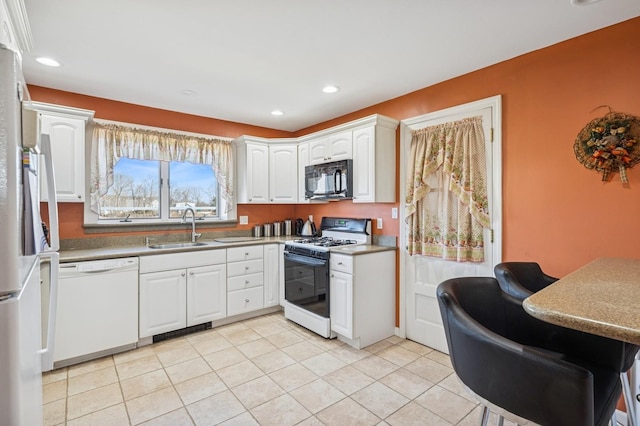 kitchen featuring light tile patterned floors, recessed lighting, white cabinets, a sink, and white appliances