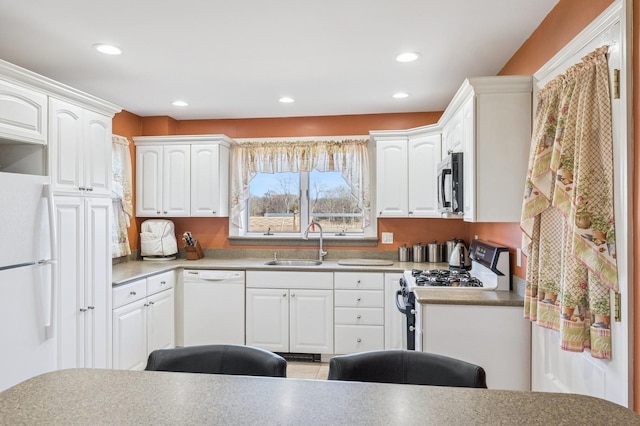 kitchen featuring white appliances, white cabinetry, a sink, and recessed lighting