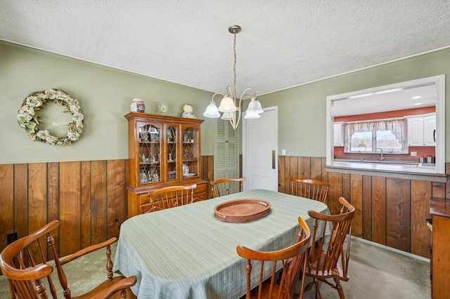 carpeted dining room with a chandelier, wainscoting, and wood walls