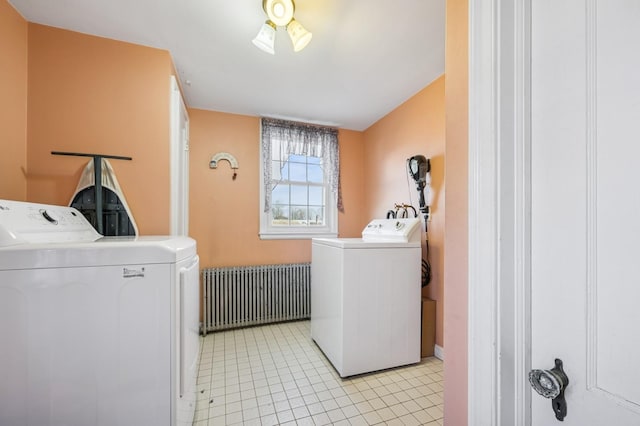 clothes washing area featuring radiator, laundry area, light tile patterned floors, and washer and clothes dryer