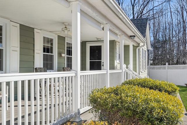 view of side of home with covered porch, fence, a ceiling fan, and roof with shingles