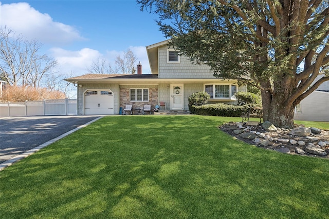 view of front of home with a garage, a chimney, aphalt driveway, fence, and a front lawn