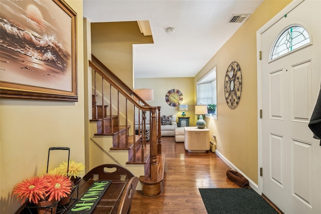 entryway with stairs, visible vents, baseboards, and wood finished floors