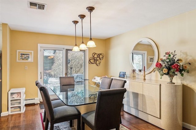 dining area with visible vents, baseboard heating, and wood finished floors