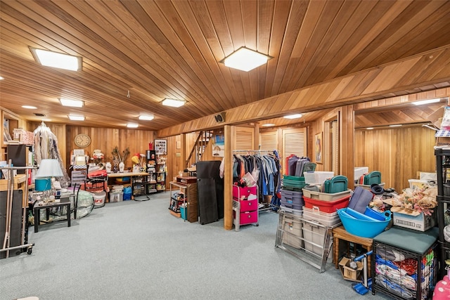 interior space featuring carpet floors, stairway, wooden ceiling, and wooden walls