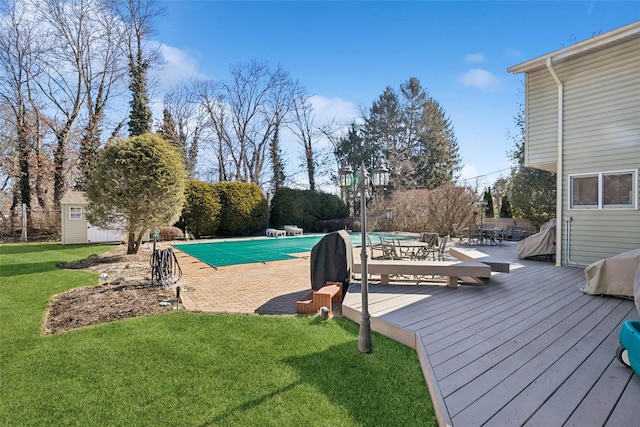 view of pool with a covered pool, an outbuilding, a deck, a yard, and a shed