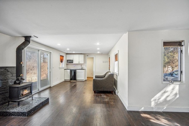 living room featuring a wood stove, plenty of natural light, baseboards, and wood finished floors