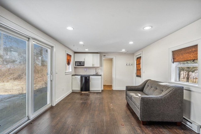 kitchen with a baseboard heating unit, dark wood finished floors, black microwave, and white cabinets