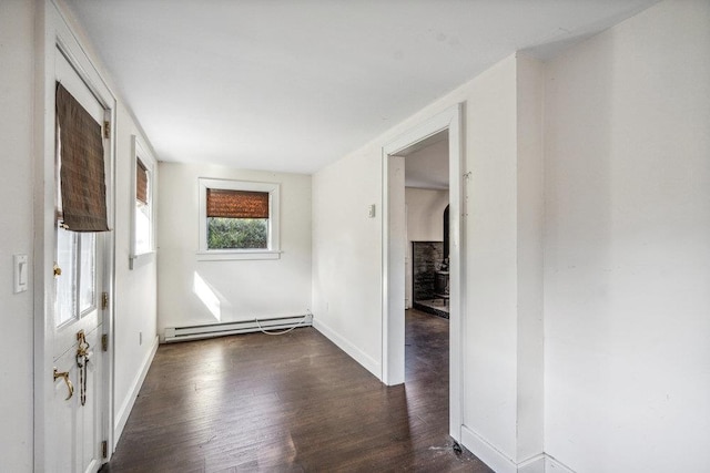 interior space featuring a baseboard heating unit, dark wood finished floors, and baseboards