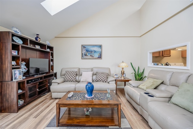 living room with high vaulted ceiling, light wood finished floors, and a skylight