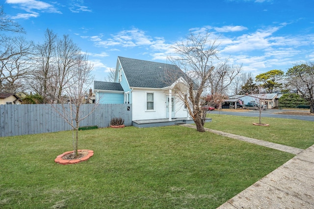 bungalow-style home featuring a front lawn, a shingled roof, fence, and stucco siding