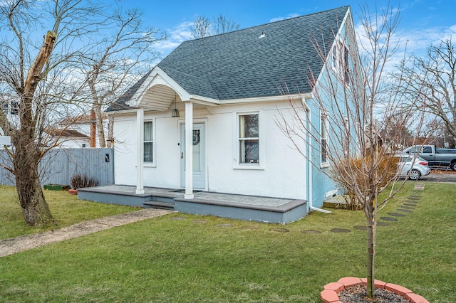 bungalow-style home featuring a shingled roof, a front lawn, fence, and stucco siding