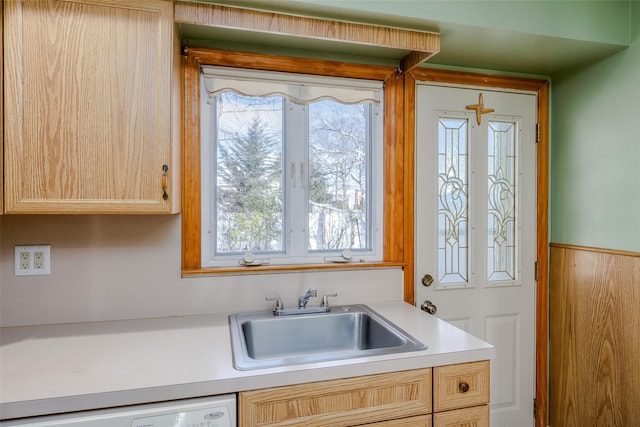 kitchen with light countertops, a sink, dishwasher, and light brown cabinetry