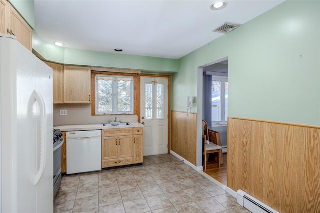 kitchen featuring a baseboard heating unit, a wainscoted wall, white appliances, a sink, and light countertops