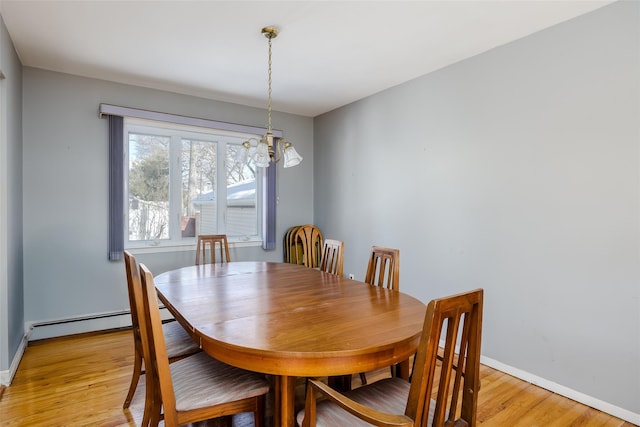 dining room featuring a baseboard heating unit, light wood-style flooring, and baseboards