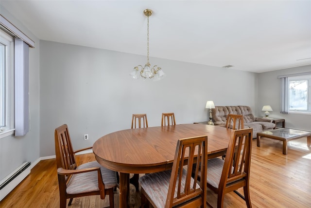 dining area with a baseboard heating unit, light wood-type flooring, baseboards, and a notable chandelier