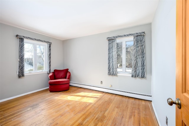 unfurnished room featuring baseboards, baseboard heating, and wood finished floors