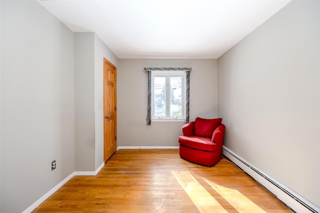 sitting room featuring a baseboard radiator, baseboards, and hardwood / wood-style flooring