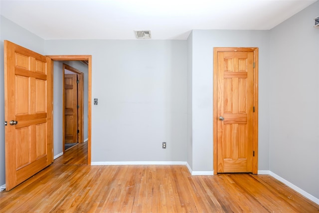 unfurnished room featuring light wood-type flooring, visible vents, and baseboards