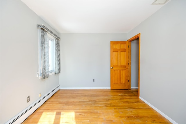 empty room with baseboards, baseboard heating, visible vents, and light wood-style floors