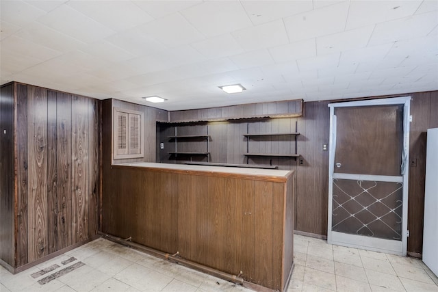 kitchen with light floors, a peninsula, wood walls, visible vents, and open shelves