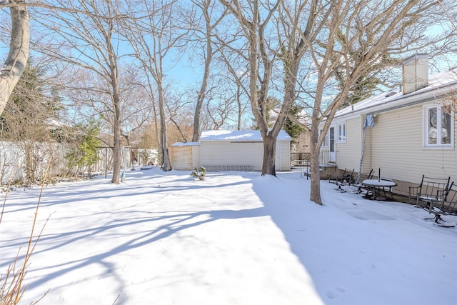 yard covered in snow with an outdoor structure, fence, and a storage unit