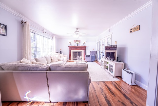 living room with ornamental molding, wood finished floors, and a glass covered fireplace